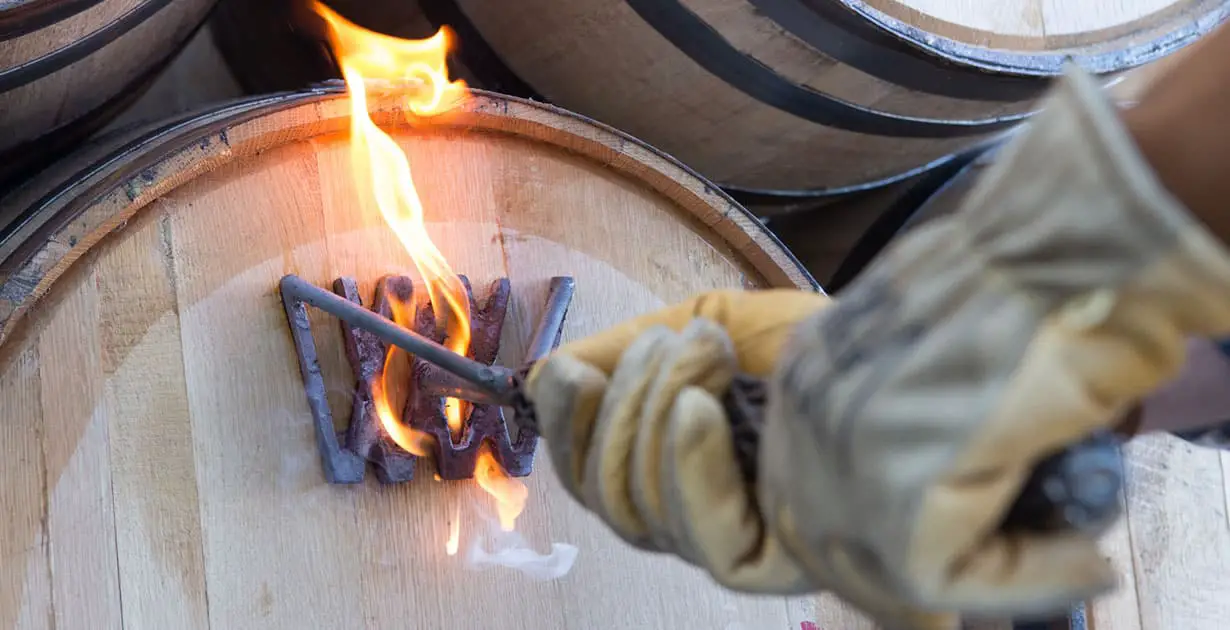 A barrel being branded with the Wyoming Whiskey logo. 